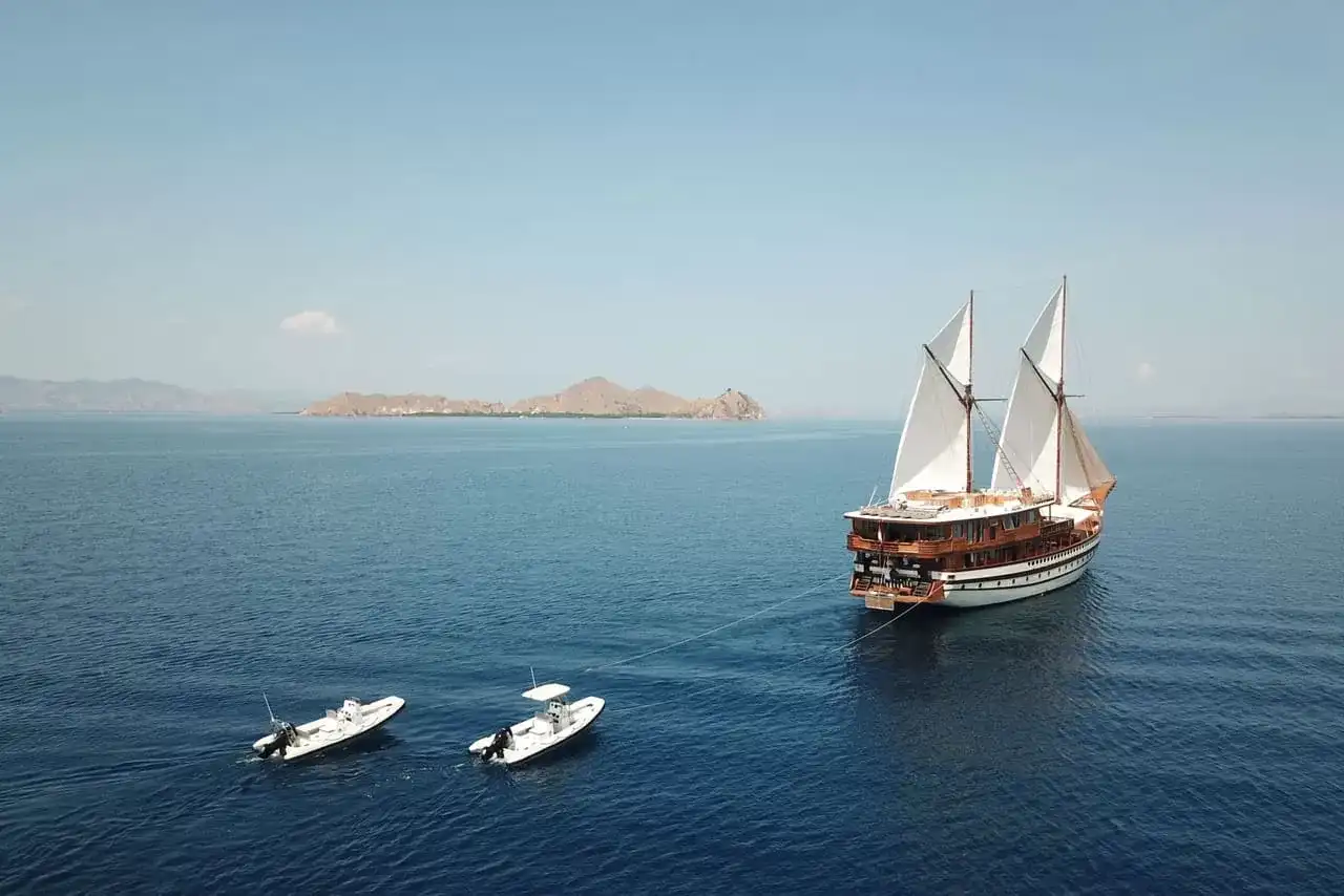 A phinisi at anchor with its tenders off a Komodo island