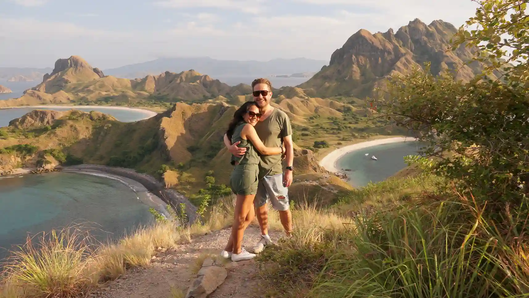Two travellers on the Padar Island ridge above three bays