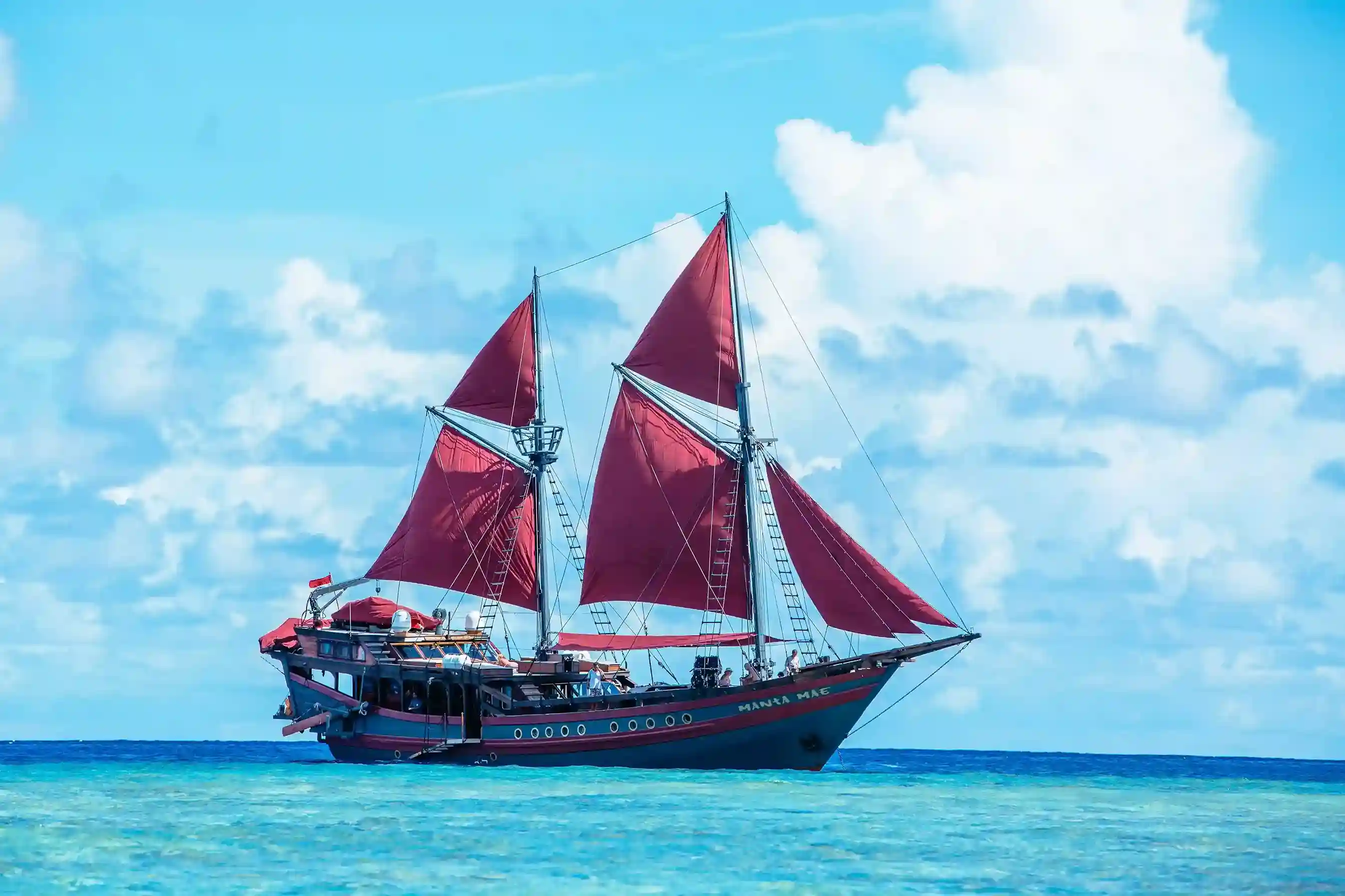 A red-sailed phinisi on turquoise water in Komodo National Park